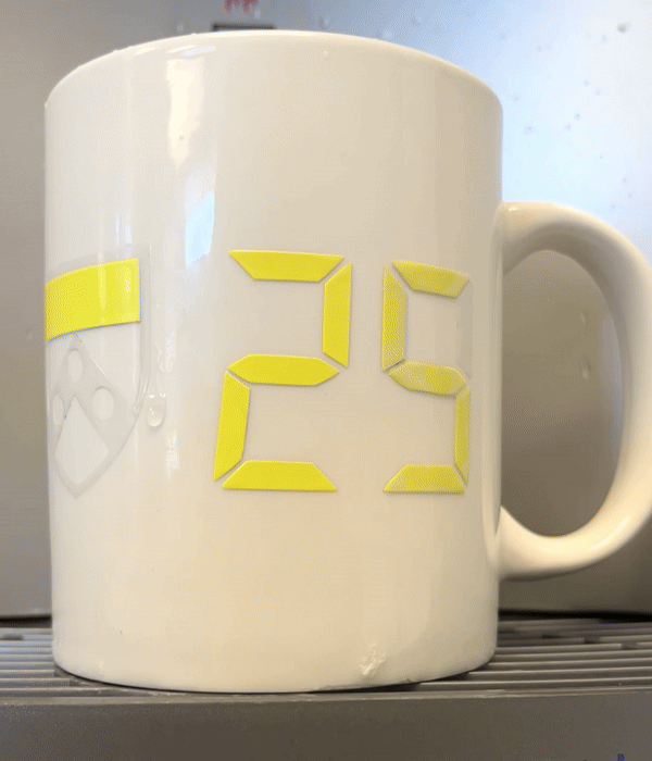 animated GIF of white mug with color-changing vinyl from yellow and clear dash and 25 to red and blue shield and 29